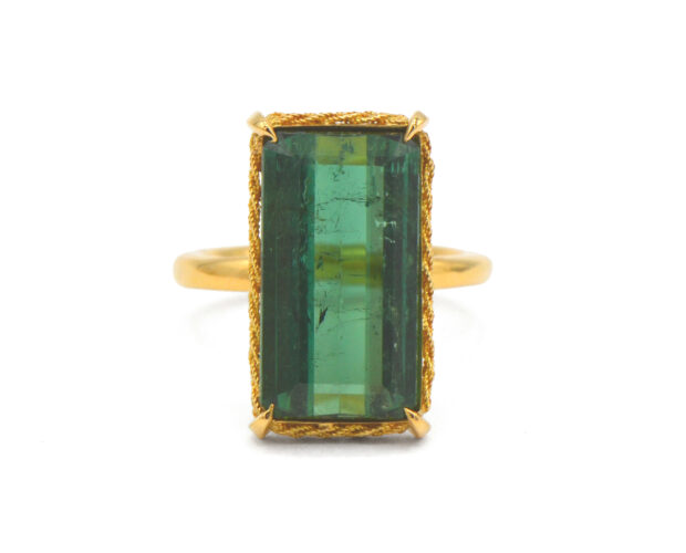 Rectangular green tourmaline with a gold braided bezel on a yellow gold shank.