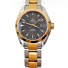 Two tone ladies Omega Seamaster watch. The watch has a dark gray stripe-textured dial, white elongated triangle markers with gold tone borders, and there is a date window on the dial at three o'clock.