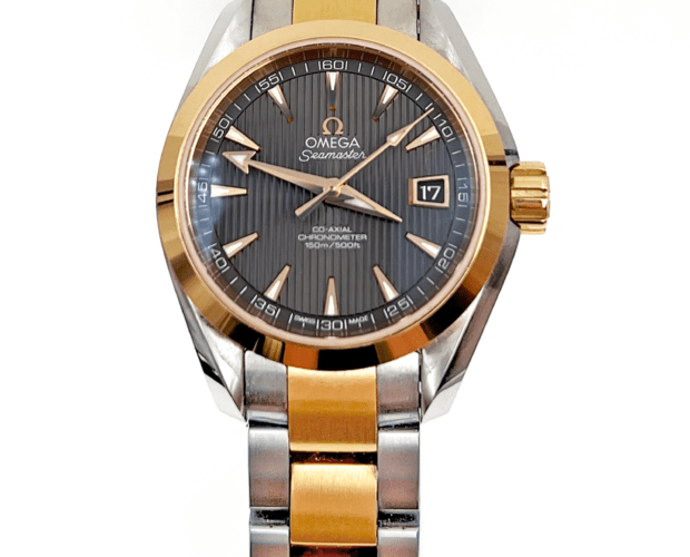 Two tone ladies Omega Seamaster watch. The watch has a dark gray stripe-textured dial, white elongated triangle markers with gold tone borders, and there is a date window on the dial at three o'clock.